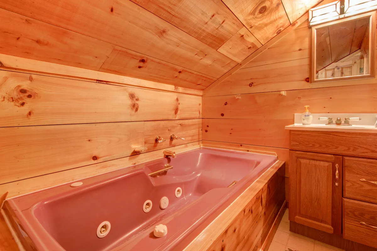 A bathroom with a luxurious jacuzzi tub set against rustic wooden walls. The wooden vanity enhances the tranquil, spa-like vibe, making it an ideal space for relaxation and rejuvenation after a long day.