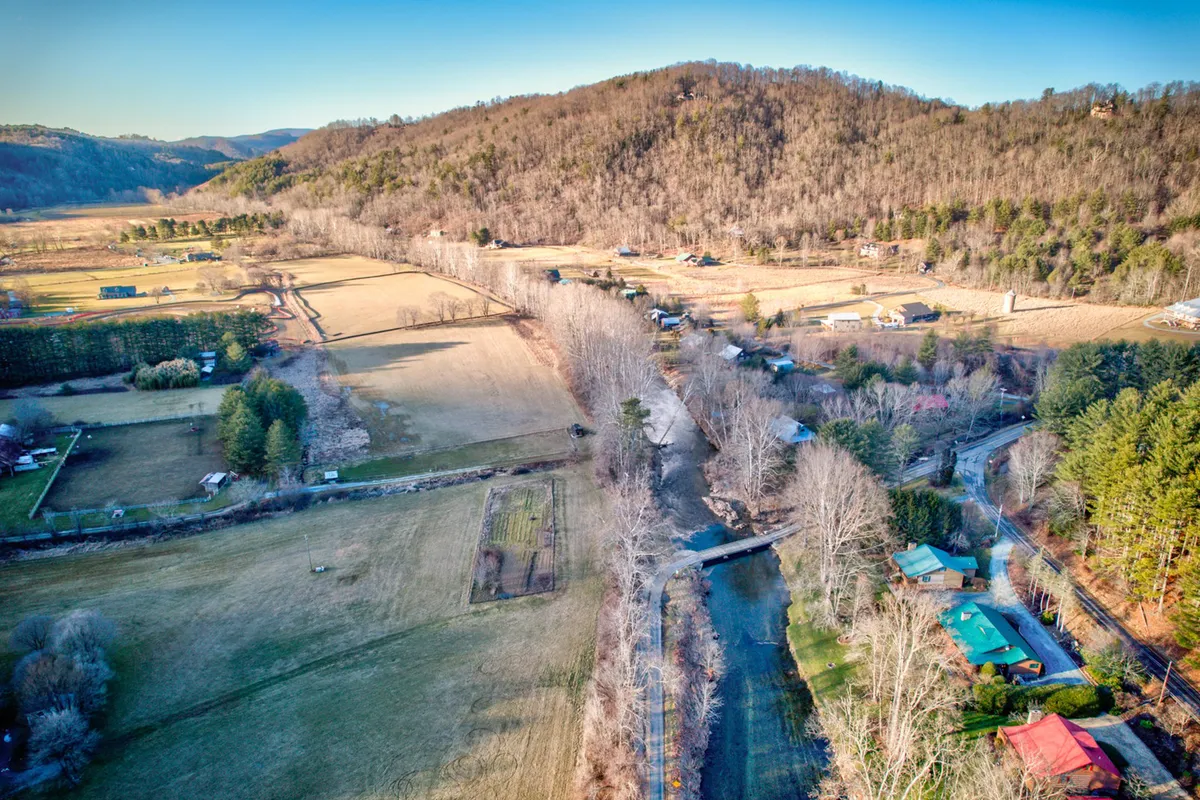 A panoramic view of rolling hills, a meandering creek, scattered homes, and farmland. The landscape glows with natural beauty and highlights the diverse terrain, making it perfect for scenic drives and hikes, especially during autumn when foliage is vibrant.